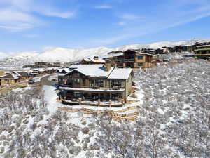 Snow covered rear of property featuring a mountain view, a balcony, a residential view, and a chimney