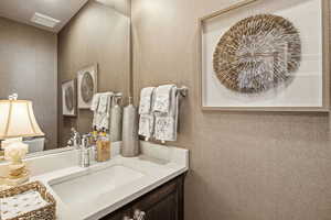 Half bath featuring vanity and a textured wall