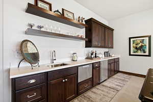 Indoor wet bar featuring open shelves, dark brown cabinets, light tile patterned floors, light stone countertops, and stainless steel appliances