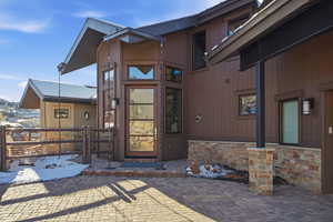Property entrance with stone siding, a gate, and a patio