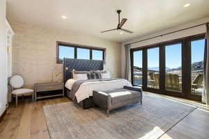 Bedroom with hardwood / wood-style flooring, wallpapered walls, a mountain view, a ceiling fan, and access to outside