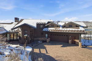 View of front of home featuring stone siding, decorative driveway, a chimney, and a mountain view