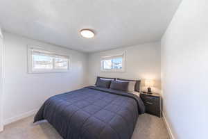 Bedroom featuring light colored carpet and a textured ceiling
