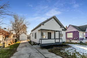 View of front of house with concrete driveway, an outbuilding, a detached garage, and covered porch