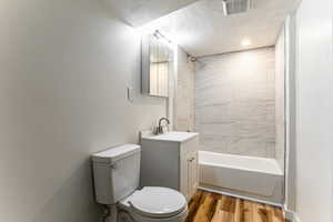 Full bath featuring vanity, a textured ceiling, shower / bathtub combination, and light wood finished floors