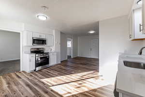 Kitchen featuring appliances with stainless steel finishes, white cabinets, light wood finished floors, and a textured ceiling