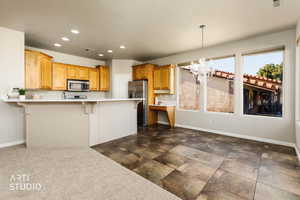Kitchen featuring recessed lighting, a kitchen bar, a chandelier, light countertops, and appliances with stainless steel finishes