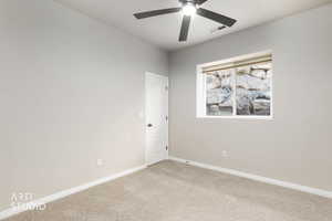 Carpeted spare room with baseboards and a ceiling fan