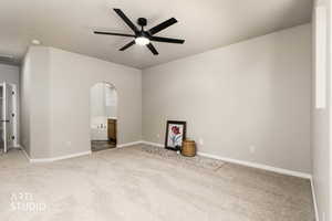 Unfurnished bedroom with ensuite bath, carpet, ceiling fan, and arched walkways
