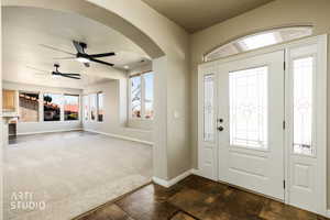 Entryway with a ceiling fan, arched walkways, dark colored carpet, and a textured ceiling