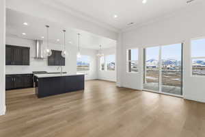 Kitchen featuring a mountain view, decorative light fixtures, an island with sink, backsplash, and a chandelier