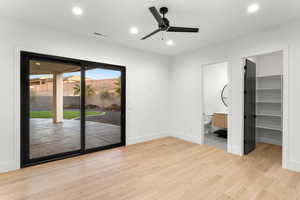 Unfurnished bedroom with a walk in closet, light wood-type flooring, access to exterior, recessed lighting, and a ceiling fan
