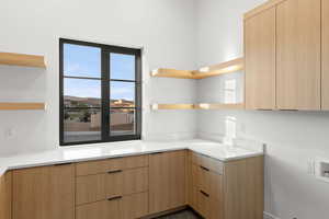 Kitchen with modern cabinets, open shelves, light brown cabinetry, and light stone countertops