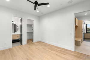 Unfurnished bedroom featuring light wood-type flooring, a spacious closet, ensuite bath, a ceiling fan, and recessed lighting