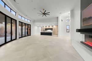 Unfurnished living room featuring a multi sided fireplace, a towering ceiling, recessed lighting, and ceiling fan