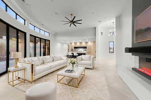 Living area with a high ceiling, a glass covered fireplace, recessed lighting, healthy amount of natural light, and a ceiling fan