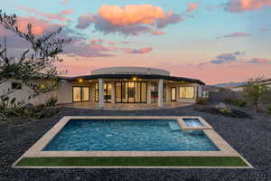 Back of house at dusk with a patio, stucco siding, a pool with connected hot tub, and a fenced backyard