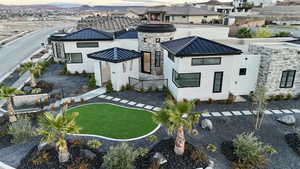 Back of property at dusk with a standing seam roof, a metal roof, stucco siding, a residential view, and a lawn