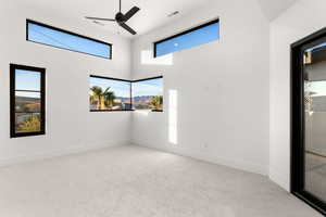 Unfurnished room with light carpet, a ceiling fan, a towering ceiling, and a mountain view