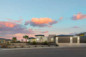 Modern home featuring a standing seam roof, a metal roof, a garage, concrete driveway, and stone siding