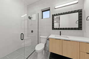 Bathroom featuring vanity, a stall shower, tile walls, and tile patterned floors
