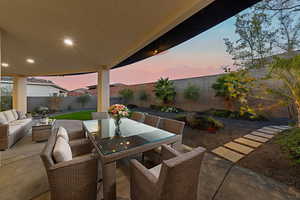 Patio terrace at dusk featuring a patio area, a fenced backyard, outdoor dining area, and an outdoor hangout area