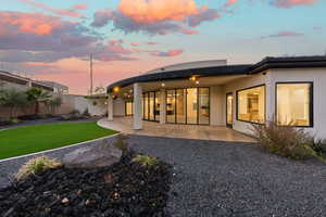 Back of house at dusk featuring a patio and stucco siding