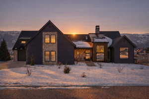 View of front of home with stone siding, a mountain view, a chimney, a garage, and a standing seam roof