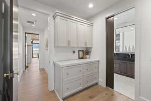Hallway with light wood-style floors and recessed lighting