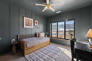 Bedroom with a decorative wall, carpet flooring, a mountain view, and ceiling fan