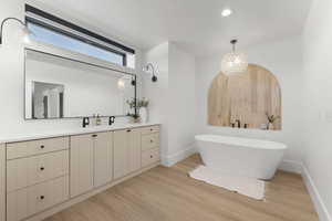 Full bath featuring vanity, a freestanding bath, light wood-style flooring, and a chandelier
