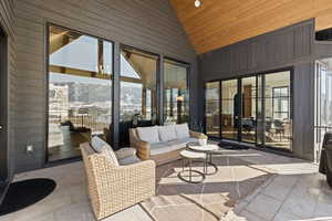 Sunroom with wood walls, tile patterned floors, high vaulted ceiling, and wooden ceiling