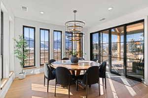 Dining area with a chandelier, a mountain view, light wood-style flooring, and recessed lighting