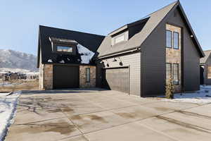 View of front of home with stone siding, concrete driveway, an attached garage, and a mountain view