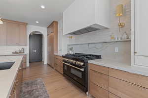 Kitchen with light stone counters, arched walkways, double oven range, modern cabinets, and recessed lighting