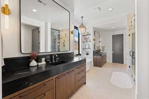Full bath featuring two vanities, a shower stall, a freestanding bath, and recessed lighting