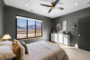 Bedroom with a mountain view, ornamental molding, light colored carpet, and ceiling fan