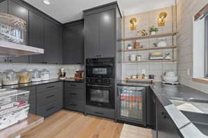 Kitchen featuring open shelves, wine cooler, light wood-style floors, and backsplash