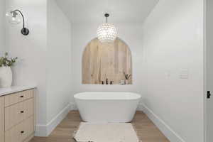 Bathroom with a freestanding tub, light wood finished floors, and a chandelier