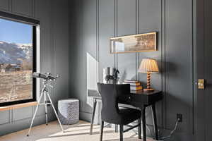 Office with a decorative wall, light colored carpet, and a mountain view