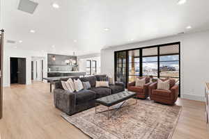 Living room with light wood-style floors, recessed lighting, and a barn door