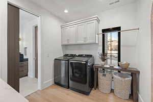 Laundry area with light wood-style floors, washing machine and dryer, cabinet space, and recessed lighting