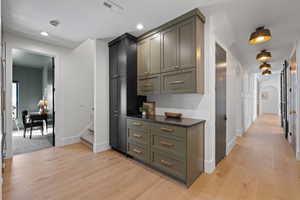 Hallway with light wood-style floors, arched walkways, stairs, and recessed lighting