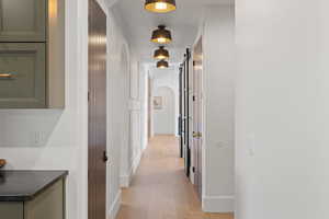 Corridor with arched walkways, a barn door, and light wood finished floors