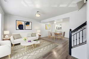 Living area with ornamental molding, wood finished floors, and stairway
