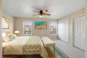Bedroom featuring two closets, carpet, and ceiling fan