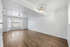Empty room with ornamental molding and wood finished floors