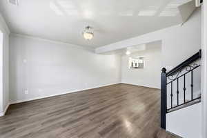 Unfurnished room with ornamental molding, dark wood-style flooring, and stairway