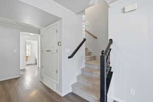 Stairway with crown molding and wood finished floors