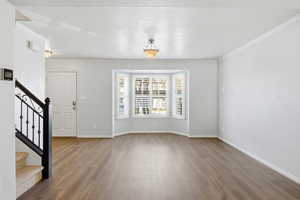 Entrance foyer with stairs, light wood-type flooring, and crown molding